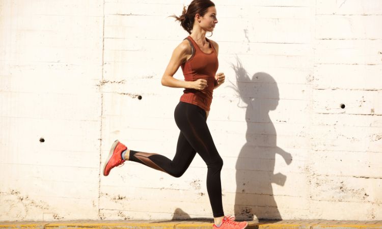 Corredora entrenando junto a un muro para preparar una carrera de 10km desde cero con un plan de entrenamiento.
